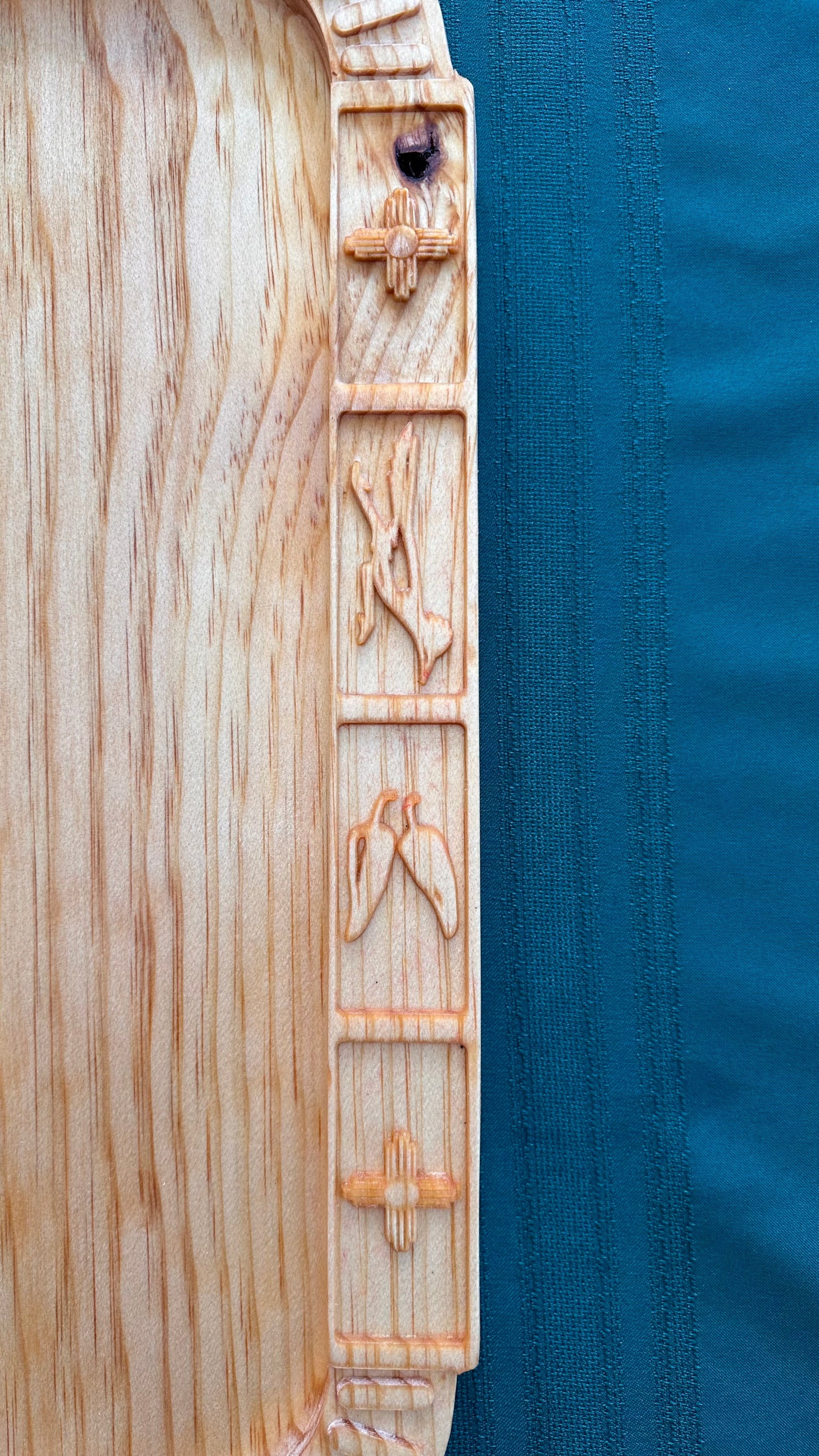 One edge of the board showcasing New Mexico designs of zia symbols (our state symbol), the roadrunner (our state bird) and chile peppers.